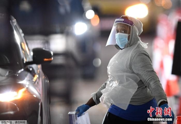 當(dāng)?shù)貢r間12月18日，英國政府公布的數(shù)據(jù)顯示，當(dāng)天英國新增奧密克戎毒株感染病例10059例。鑒于奧密克戎毒株感染病例激增，住院人數(shù)不斷上升，倫敦市長宣布倫敦進(jìn)入“重大事故”狀態(tài)。圖為倫敦的一個免下車檢測中心，一名醫(yī)務(wù)工作者正準(zhǔn)備對司機進(jìn)行核酸檢測。