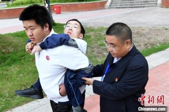 朱金祥背著鐘華強(qiáng)去教室上課的路上，也經(jīng)常碰到值班的校領(lǐng)導(dǎo)和老師前來搭把手。 卓忠偉 攝