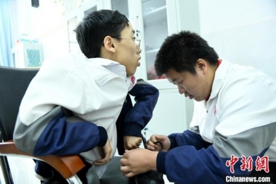 江西省南康中學(xué)北校區(qū)的高三學(xué)生朱金祥(右)正在給鐘華強(qiáng)(左)系好鞋帶。 卓忠偉 攝