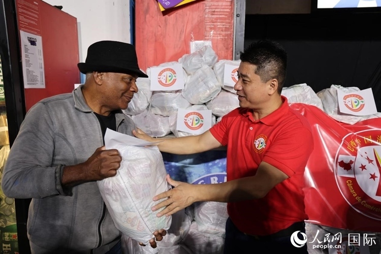巴西中國浙江商會會長鄭俠茂向社區(qū)居民轉(zhuǎn)交捐贈物資。人民網(wǎng)記者 時元皓攝