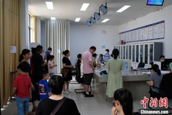 圖為在戶籍辦證廳內(nèi)排隊(duì)等待的家長和孩子。劉俊聰 攝