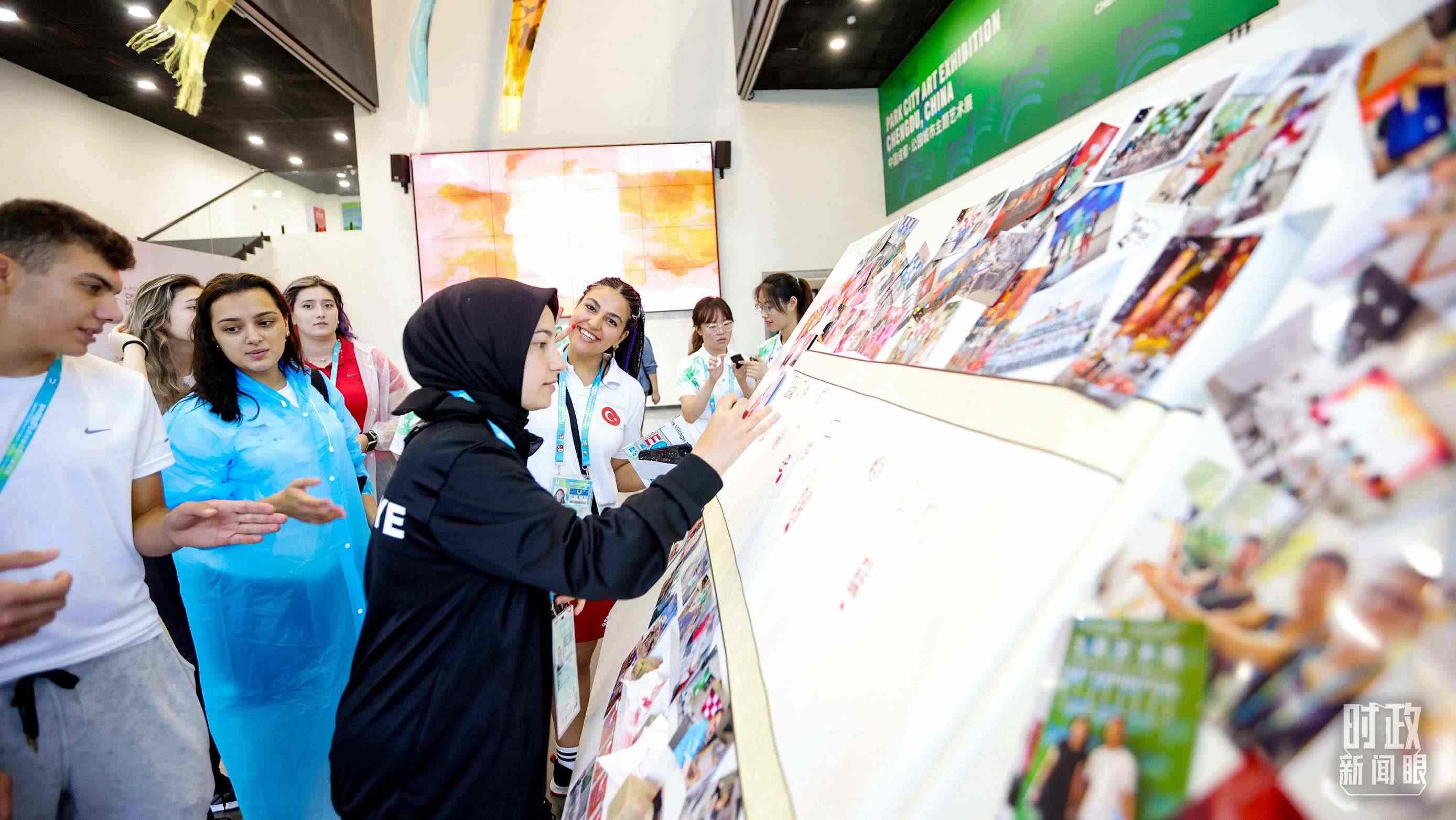 各國(guó)青年運(yùn)動(dòng)員正在參觀成都大運(yùn)村內(nèi)的“雪山下的公園城市，煙火里的幸福成都”主題藝術(shù)展。（總臺(tái)央視記者魏幫軍拍攝）