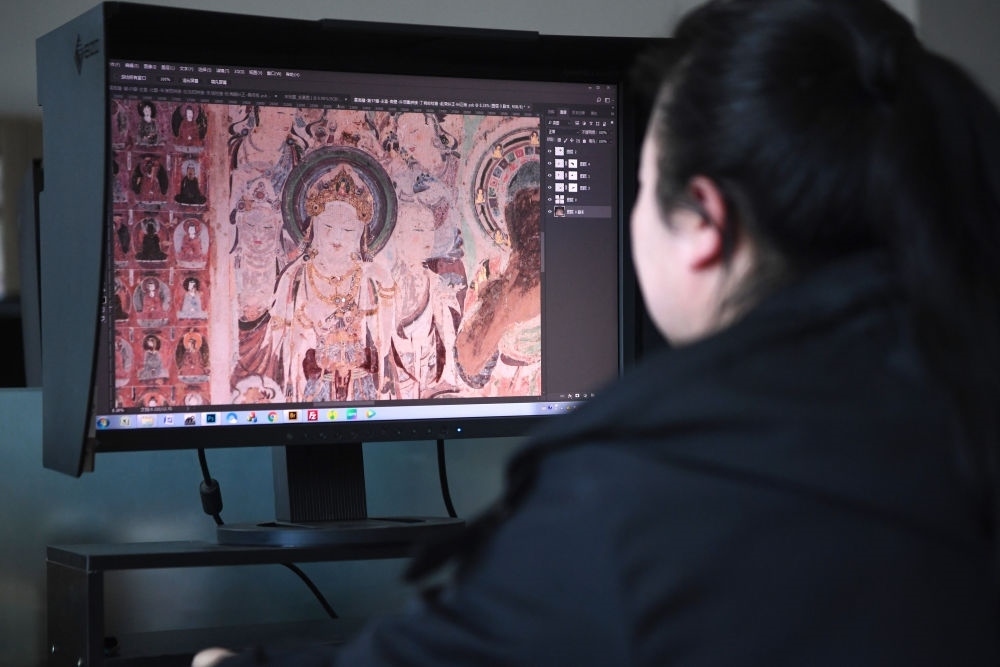 敦煌研究院文物數(shù)字化保護團隊圖像處理人員年海麗在拼接壁畫圖像（2023年4月25日攝）。數(shù)字化探索為莫高窟的保護與傳承開辟了全新路徑，數(shù)字技術讓敦煌文物走出洞窟，跨出國門，走向“永久保存、永續(xù)利用”。新華社記者 陳斌 攝