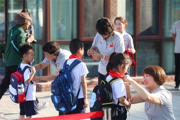 8月30日，雄安史家胡同小學(xué)學(xué)生體驗(yàn)學(xué)校生活。老師為學(xué)生佩戴?；?。