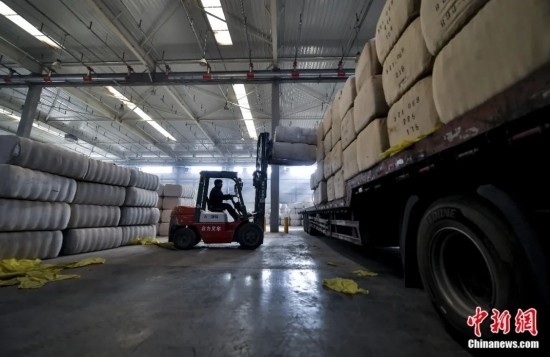 新疆喀什綜合保稅區(qū)，喀什啟路國(guó)際貿(mào)易有限公司的倉(cāng)庫(kù)內(nèi)，工人正在裝載從塔吉克斯坦和烏茲別克斯坦進(jìn)口的棉花。劉新攝