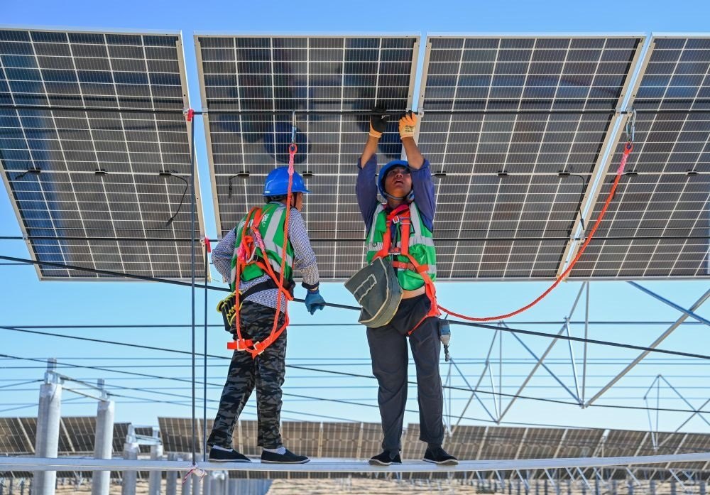 2023年7月22日，工人在位于內(nèi)蒙古杭錦旗庫(kù)布其沙漠億利生態(tài)示范區(qū)的蒙西基地庫(kù)布其200萬(wàn)千瓦光伏治沙項(xiàng)目工地安裝光伏板。新華社記者 劉磊 攝