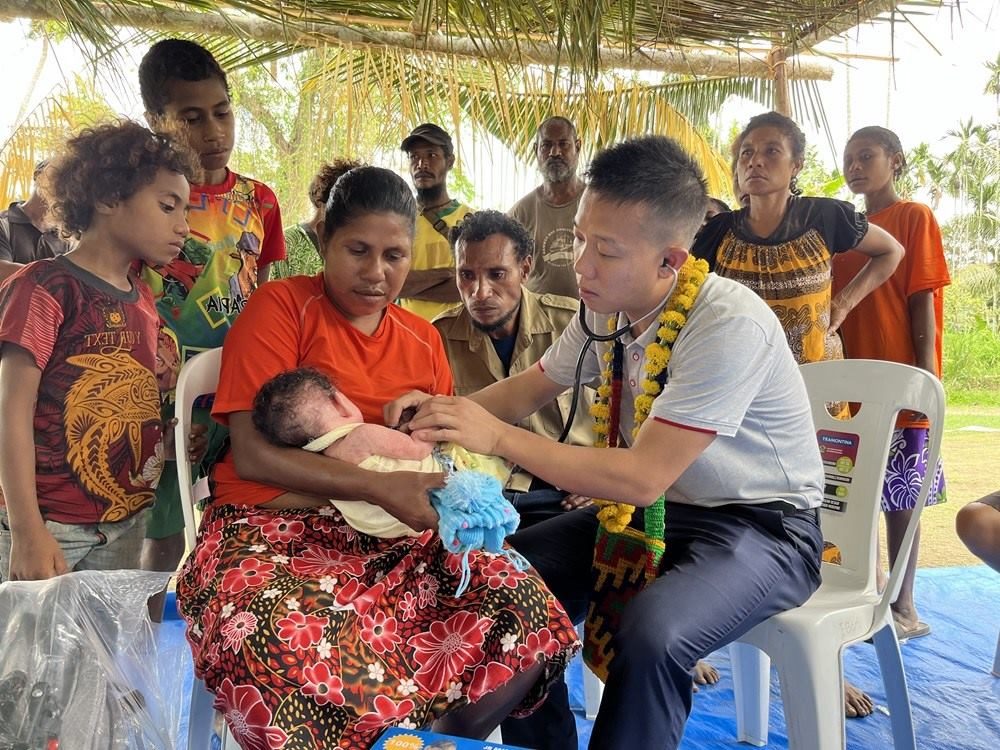 2023年8月5日，在巴布亞新幾內(nèi)亞中央省的一個(gè)村莊里，第12批援巴新中國(guó)醫(yī)療隊(duì)副隊(duì)長(zhǎng)、新生兒科副主任醫(yī)師劉振球?yàn)楫?dāng)?shù)貗雰郝犜\檢查。新華社發(fā)（第12批援巴新中國(guó)醫(yī)療隊(duì)供圖）