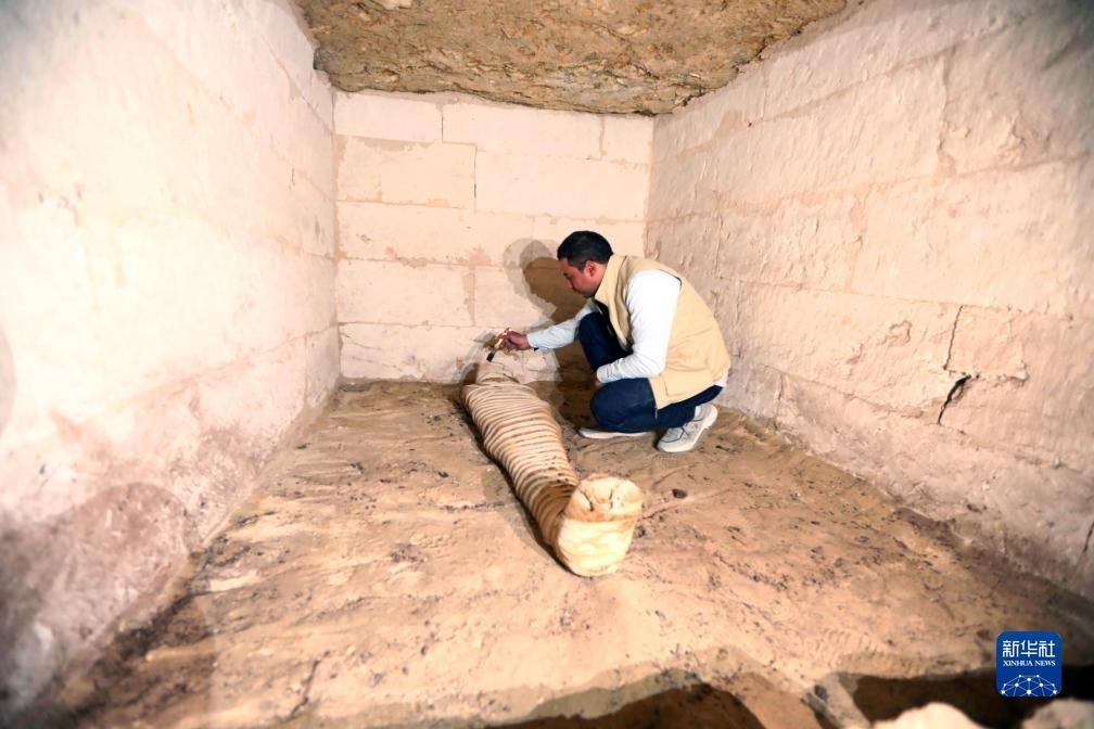 10月15日，在埃及明亞省考古現(xiàn)場，考古人員清理一座石鑿墓中的木乃伊。新華社發(fā)（艾哈邁德·戈馬攝）