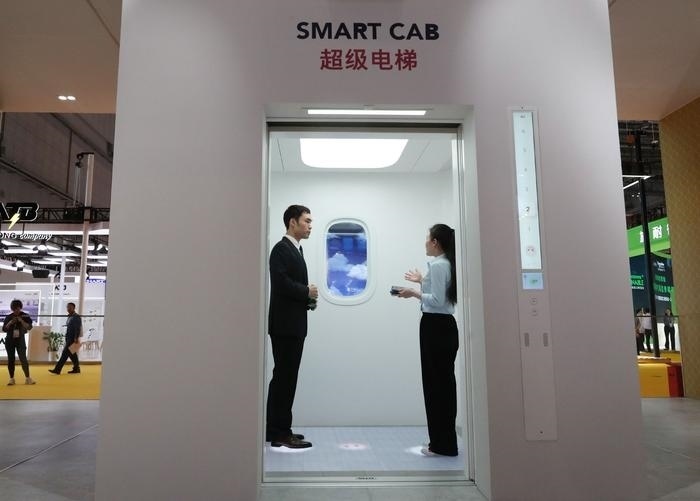 11月5日，工作人員（右）在第六屆進(jìn)博會上向參觀者介紹奧的斯公司全新推出的超級電梯。