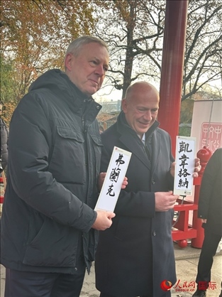 柏林市長韋格納（右）、動物園監(jiān)事會主席布魯克曼（左）手持中國文化中心工作人員現(xiàn)場手書的中文名字。人民網(wǎng)記者 徐馨攝