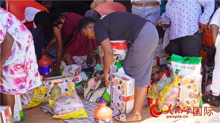 當(dāng)?shù)厣鐓^(qū)家庭領(lǐng)取物資。人民網(wǎng) 張茜攝