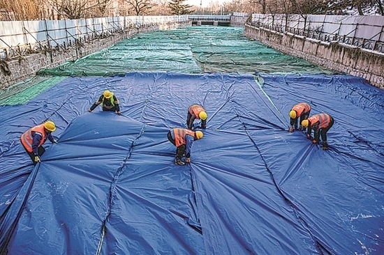 1月3日，房山區(qū)東風(fēng)街道，工人正在修復(fù)的河道內(nèi)給混凝土鋪設(shè)保溫布。