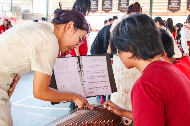 志愿者教師指導(dǎo)學(xué)生彈奏古箏。活動主辦方供圖