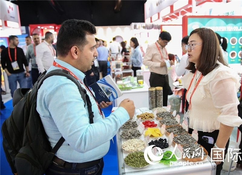 圖為一家中國干果參展企業(yè)代表與采購商洽談。人民網(wǎng) 塔里克·易卜拉欣攝