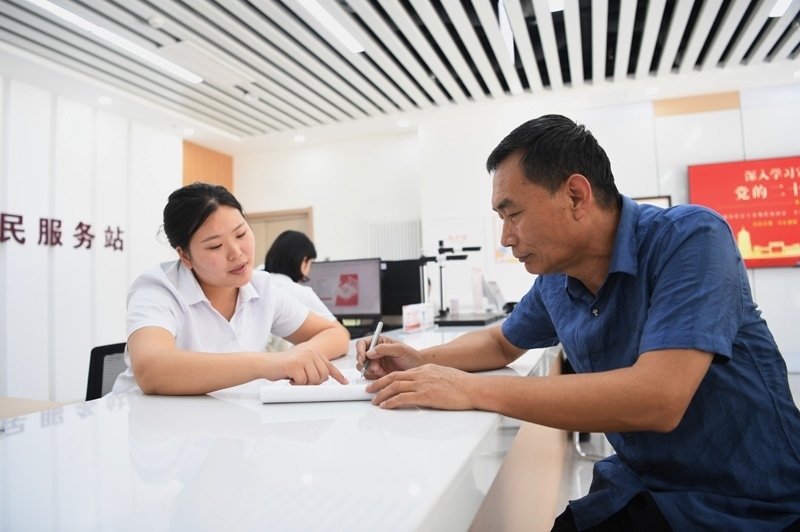 2023年5月23日，河北雄安新區(qū)容東片區(qū)南文營社區(qū)居民（右）在社區(qū)便民服務(wù)站辦理業(yè)務(wù)。