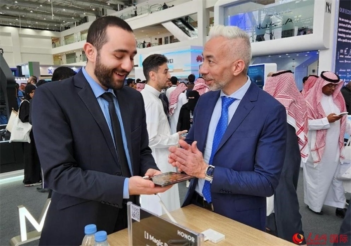 兩名觀眾在榮耀手機(jī)展臺前交流。人民網(wǎng)記者 管克江攝