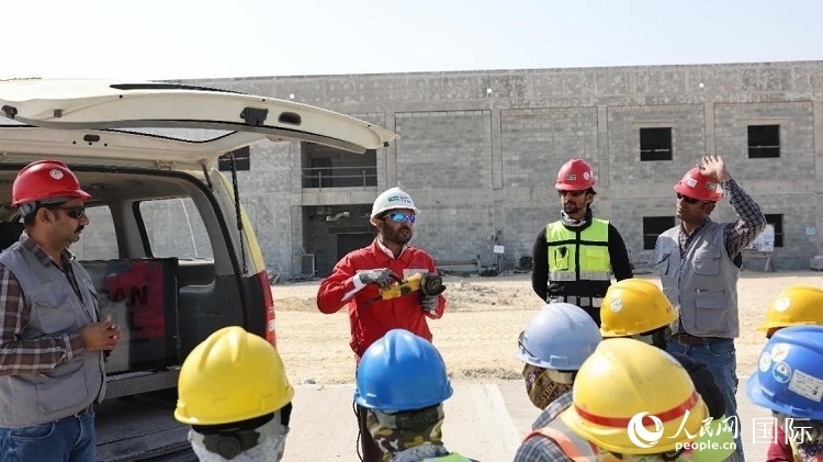 穆薩瓦爾(圖中紅衣人）現(xiàn)場(chǎng)演示工具操作規(guī)范。人民網(wǎng)記者 管克江攝