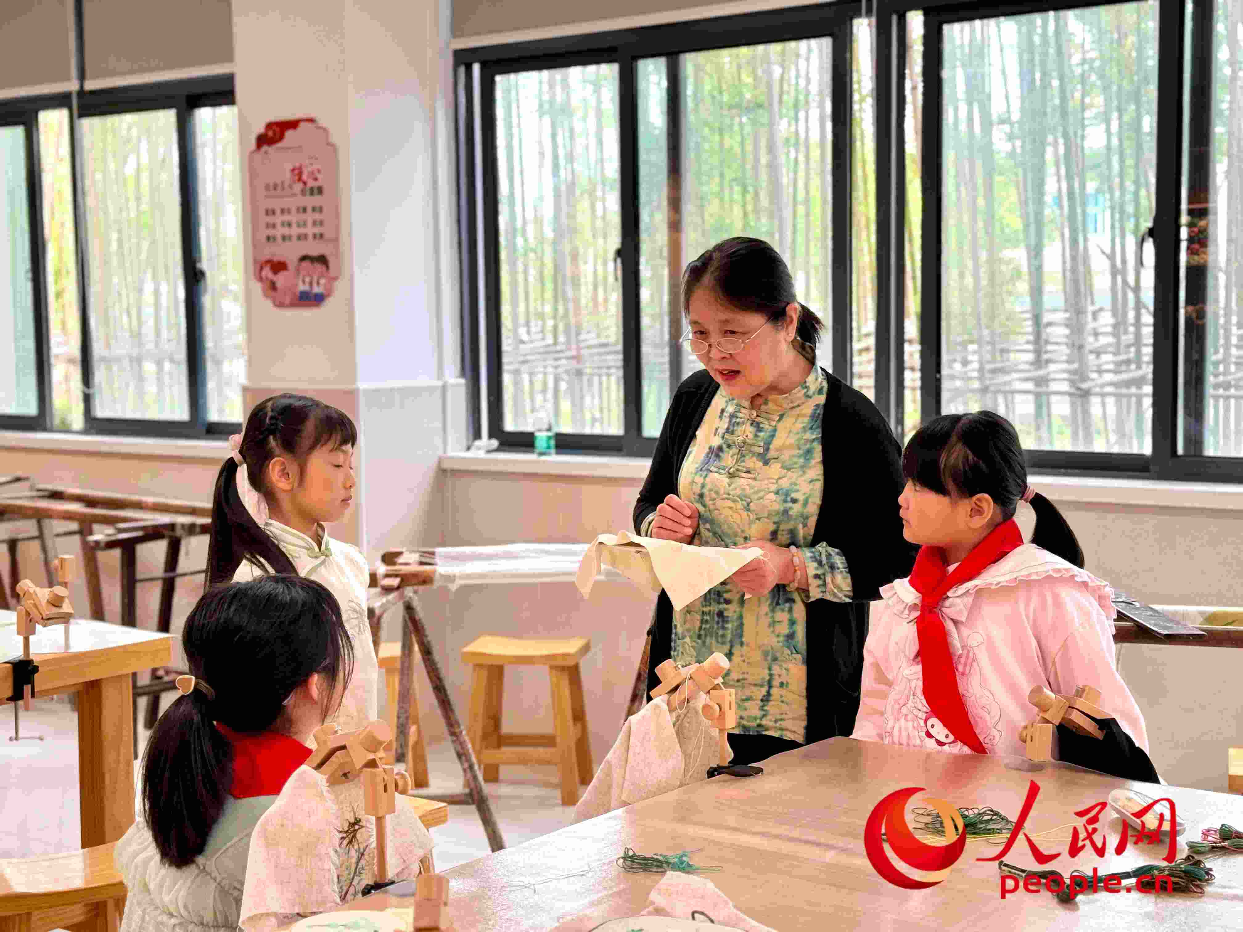 顧建珍（左三）在教孩子們刺繡知識(shí)。人民網(wǎng) 周靜圓攝