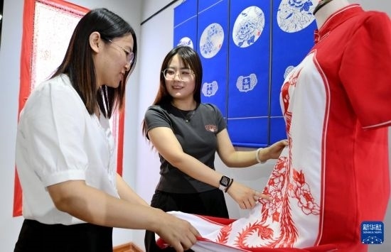 5月31日，在衡水市阜城縣一家剪紙工作室，游客在觀賞帶有剪紙?jiān)氐钠炫邸? width=