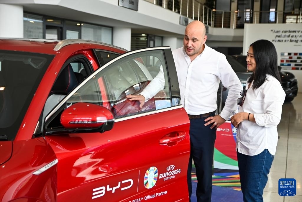 2024年5月29日，在馬耳他比爾基卡拉，馬耳他哈桑-扎米特汽車公司首席執(zhí)行官德古阿拉（左）介紹一輛比亞迪純電動汽車。新華社發(fā)（喬納森·博格 攝）