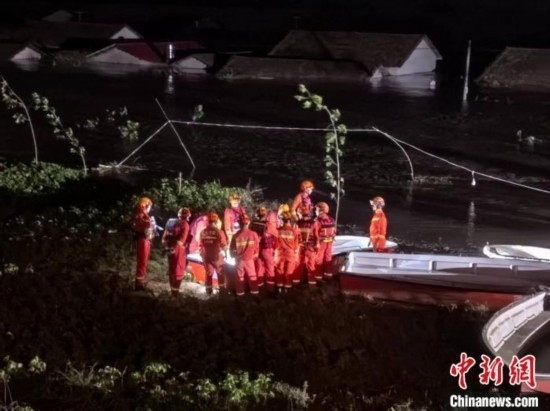  7月6日凌晨3時，在湖南岳陽華容縣團洲垸洞庭湖一線堤防，救援人員剛剛完成一次救援任務，遠處是被淹的民房。中新社記者 白祖偕 攝