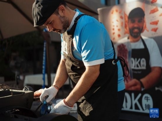 7月19日，在蕪湖古城，馬丁在當(dāng)天舉行的啤酒節(jié)上制作牛排。新華社發(fā)（繆雨晨 攝）