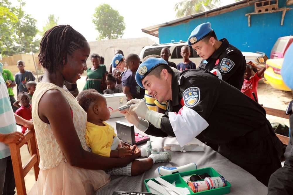 2017年12月28日，在利比里亞蒙羅維亞，中國維和警察防暴隊醫(yī)療人員為兒童做口腔檢查。