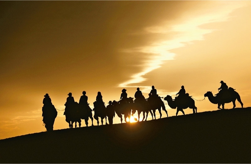 新時(shí)代以來，文化和旅游深度融合發(fā)展體制機(jī)制不斷健全，成功走出了一條獨(dú)具特色的中國旅游發(fā)展之路。圖為2024年9月1日清晨，游客在甘肅省敦煌市鳴沙山月牙泉景區(qū)乘騎駱駝，欣賞大漠風(fēng)光，體驗(yàn)絲路風(fēng)情。 新華社發(fā) 張曉亮/攝