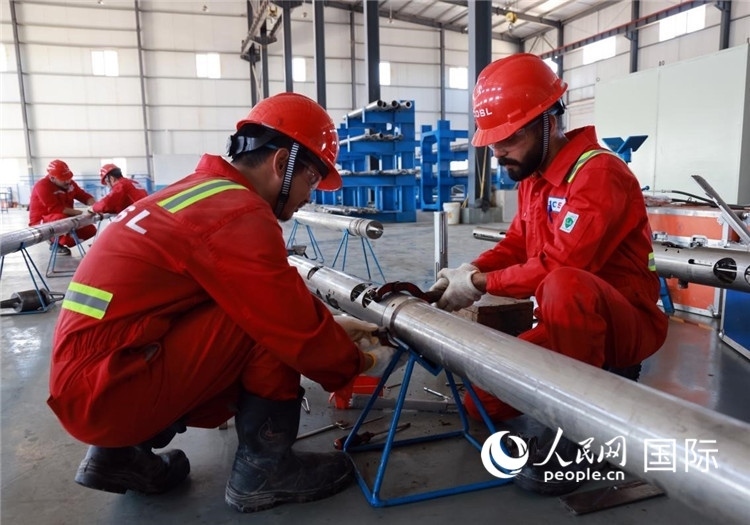 中伊員工共同在檢修鉆井設(shè)備。人民網(wǎng)記者管克江攝