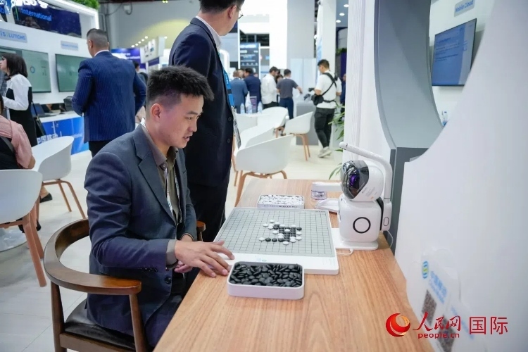 觀眾在中國移動國際有限公司展臺體驗智慧圍棋機(jī)器人。人民網(wǎng) 塔里克·易卜拉欣攝