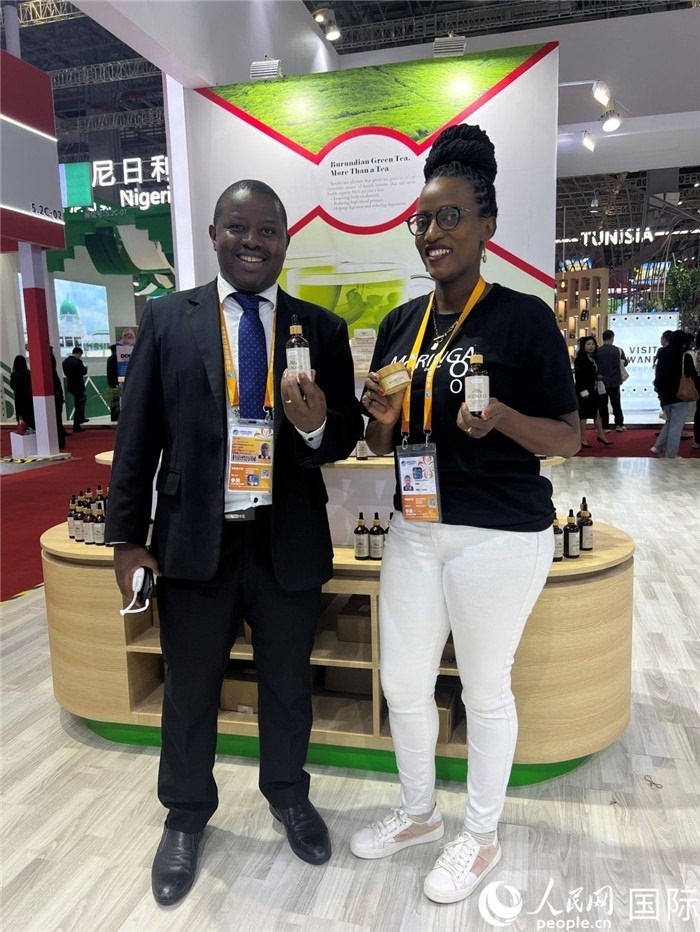 6月6日，布隆迪駐華大使館一等參贊布利馬索·阿爾弗雷德 (左，Bulimaso Alfred) 和參展商卡馬里扎·埃斯特拉 (Kamariza Estella) 在第七屆中國國際進口博覽會布隆迪館展示當?shù)厣a的辣木油。（人民網 艾里士 攝）