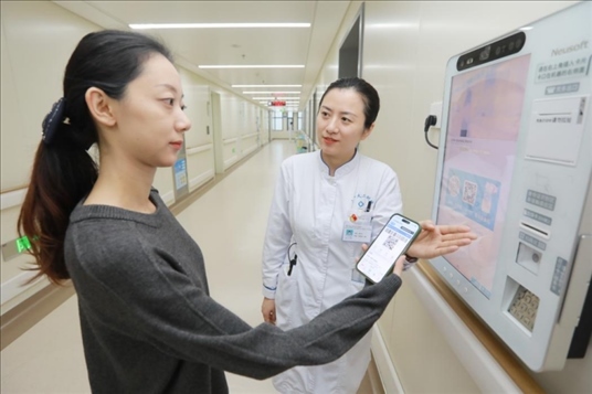 醫(yī)護人員引導患者在自助機前辦理自助入院手續(xù)。圖片來源：山東第一醫(yī)科大學第二附屬醫(yī)院