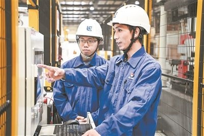在廣西柳工機(jī)械股份有限公司生產(chǎn)車間內(nèi)，一名高級(jí)技師（右）給徒弟講解數(shù)控設(shè)備操作細(xì)節(jié)。新華社記者 曹祎銘攝