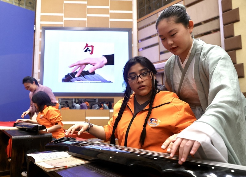 2024年3月20日，美國華盛頓州中學(xué)生代表團(tuán)北京大學(xué)交流活動(dòng)在北京大學(xué)英杰交流中心舉行。圖為來自華盛頓州的中學(xué)生體驗(yàn)古琴。