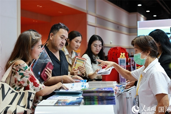 外國(guó)觀眾在中國(guó)展臺(tái)仔細(xì)閱讀赴華旅游介紹，向工作人員咨詢關(guān)于中國(guó)美食和景點(diǎn)的詳細(xì)信息。人民網(wǎng)記者 白元琪攝