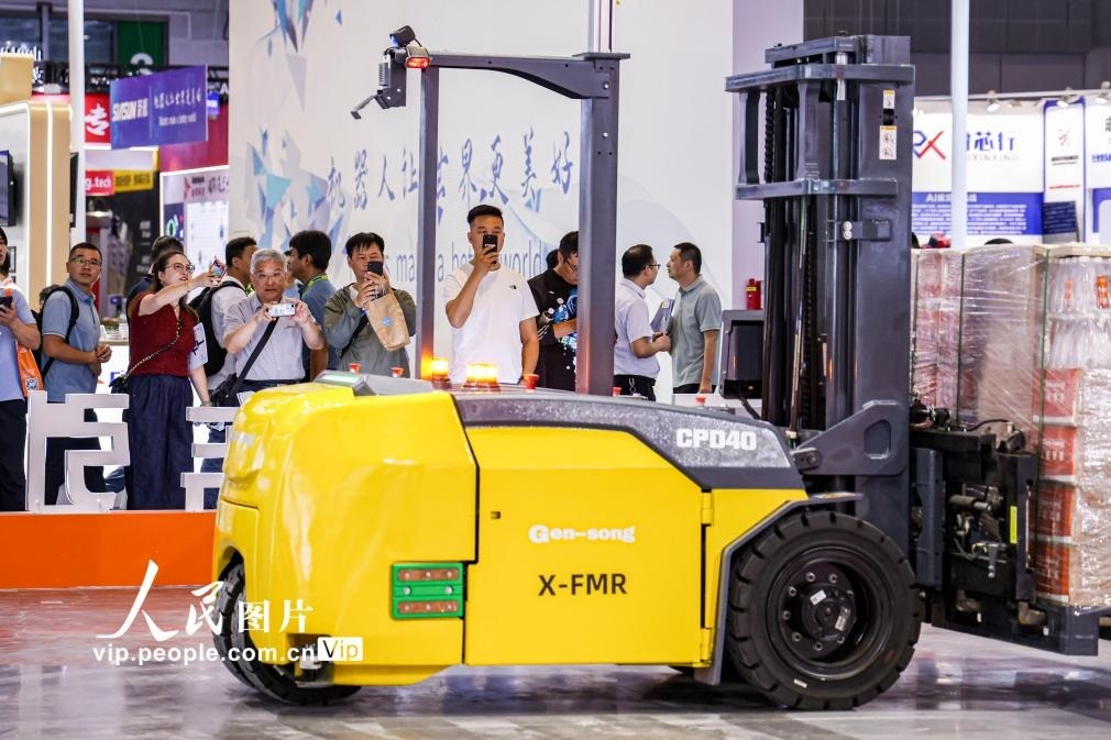 第24屆中國工博會現(xiàn)場，觀眾觀看叉取機器人作業(yè)演示。王初攝（人民圖片網(wǎng)）