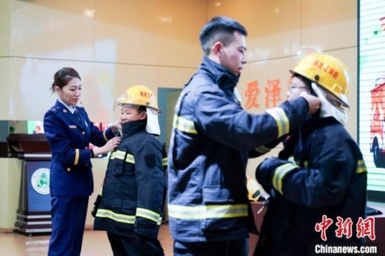 圖為學(xué)生們現(xiàn)場穿戴消防頭盔和戰(zhàn)斗服。中新社記者 趙宇航 攝