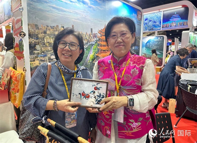 中國“大冶刺繡”傳承人劉小紅（右）參加泰國國際旅游展，向觀眾介紹中國非遺刺繡針法。人民網(wǎng)記者 簡承淵攝
