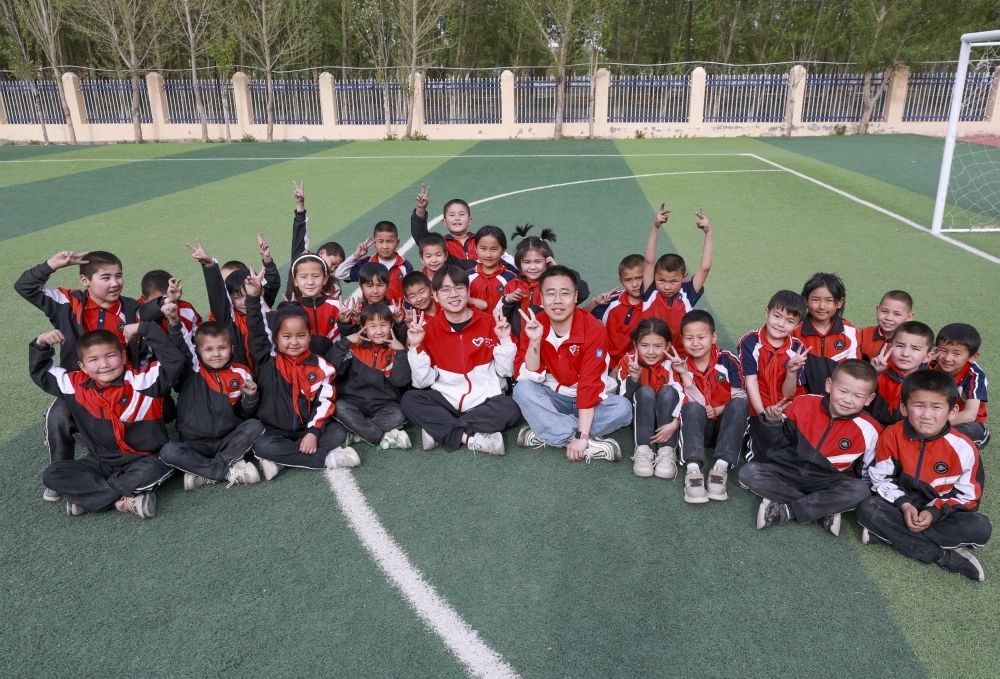 4月23日，在新疆克州阿圖什市哈拉峻鄉(xiāng)謝依特小學(xué)，支教教師王俊文（中左）、李軻凡（中右）和學(xué)生在一起。