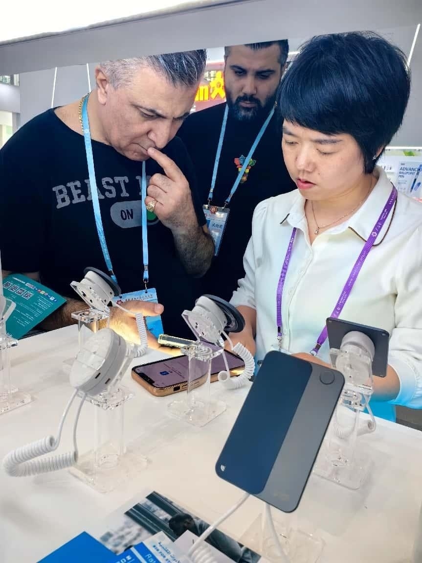 展臺(tái)工作人員向外商展示“AI TOP翻譯終端”。圖片來源：受訪者提供