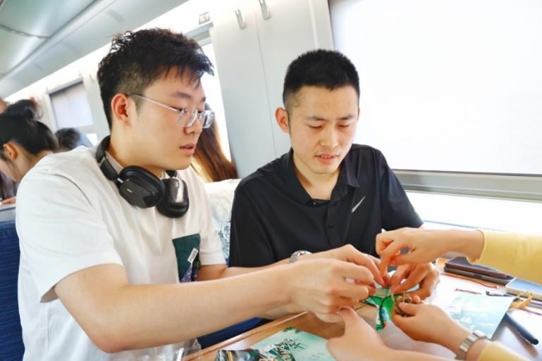 G232次旅客親手制作端午荷包和五彩繩。王磊攝